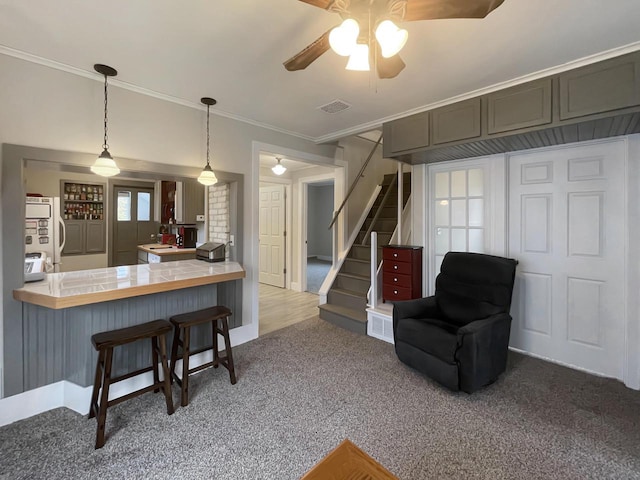 kitchen with hanging light fixtures, a kitchen breakfast bar, white refrigerator, kitchen peninsula, and crown molding