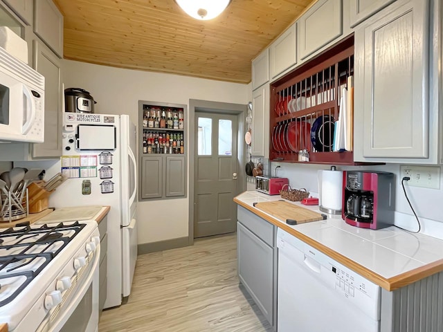 kitchen with tile countertops, white appliances, gray cabinets, light wood-type flooring, and wood ceiling