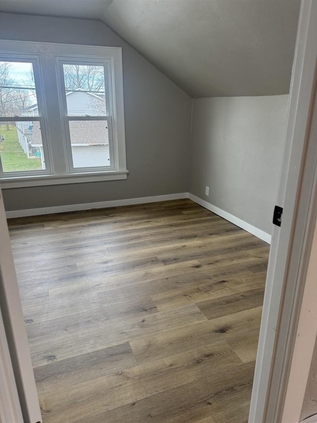 bonus room featuring baseboards, vaulted ceiling, and wood finished floors