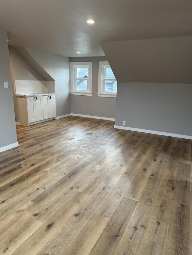 additional living space with lofted ceiling, light wood finished floors, recessed lighting, and baseboards