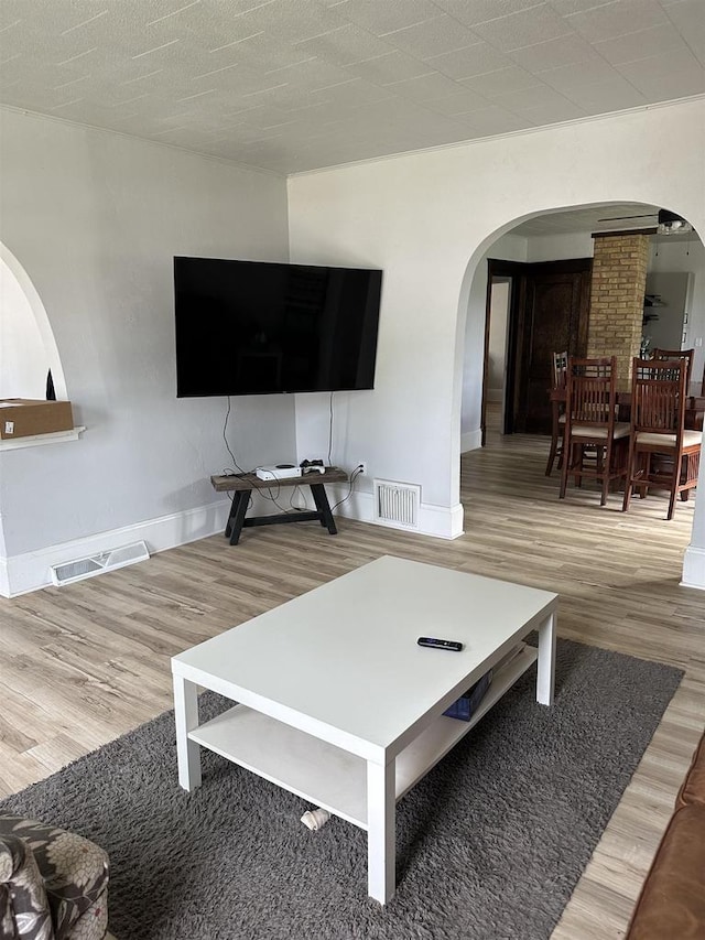 living area featuring arched walkways, visible vents, and wood finished floors