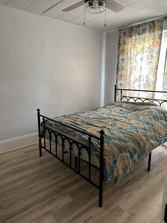 bedroom with ceiling fan, baseboards, and wood finished floors