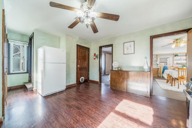 interior space with ceiling fan, white refrigerator, and dark wood-type flooring