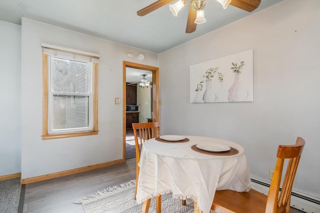 dining area with a baseboard heating unit and light wood-type flooring