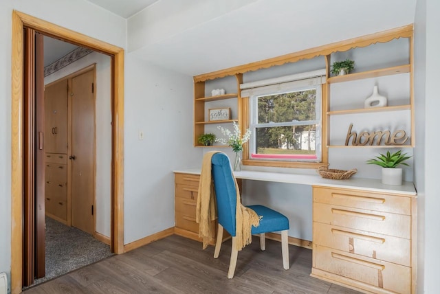 home office featuring dark hardwood / wood-style flooring and built in desk