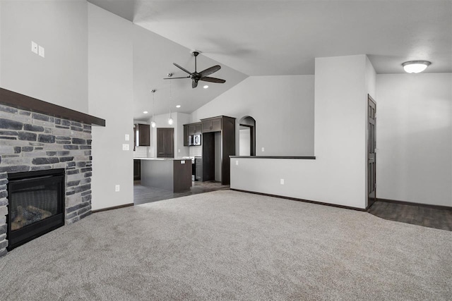 unfurnished living room with ceiling fan, a fireplace, high vaulted ceiling, and dark colored carpet