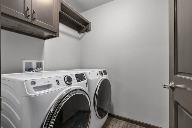 washroom featuring washing machine and dryer, dark hardwood / wood-style flooring, and cabinets