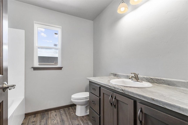 bathroom with vanity, a bathtub, toilet, and wood-type flooring