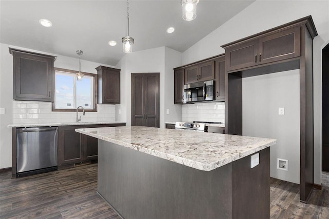 kitchen featuring dark hardwood / wood-style floors, decorative light fixtures, stainless steel appliances, and vaulted ceiling