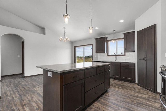 kitchen featuring a center island, backsplash, dark wood-type flooring, vaulted ceiling, and decorative light fixtures