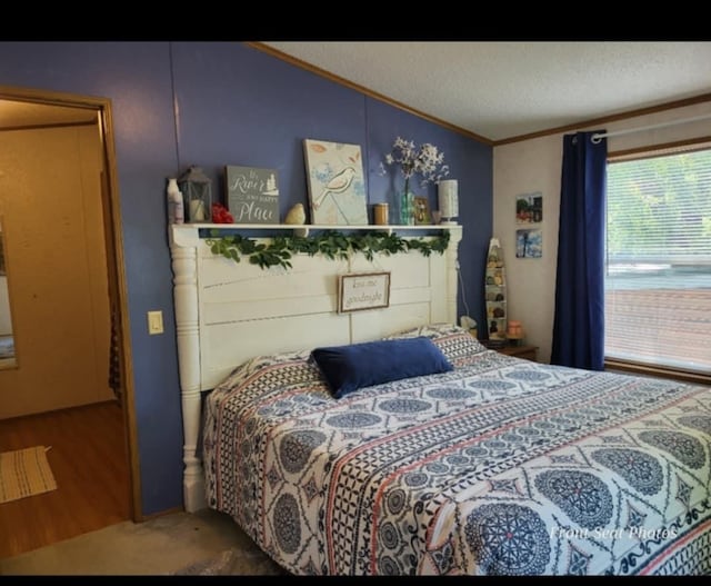 bedroom with hardwood / wood-style floors, a textured ceiling, lofted ceiling, and ornamental molding