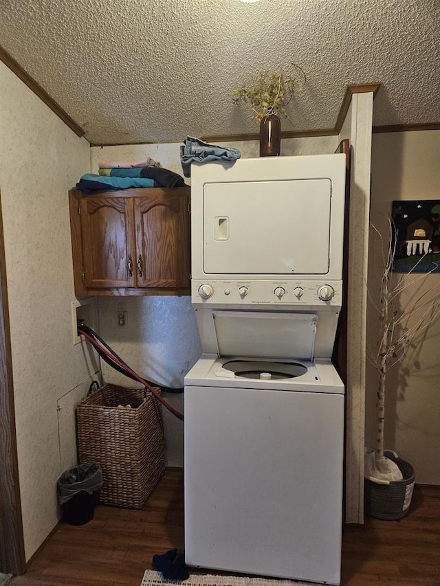 washroom with cabinets, dark hardwood / wood-style floors, ornamental molding, a textured ceiling, and stacked washer / drying machine