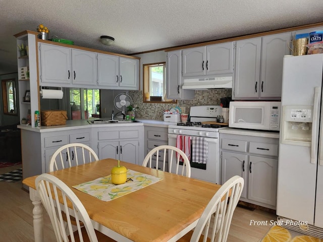 kitchen with sink, tasteful backsplash, light hardwood / wood-style flooring, a textured ceiling, and white appliances