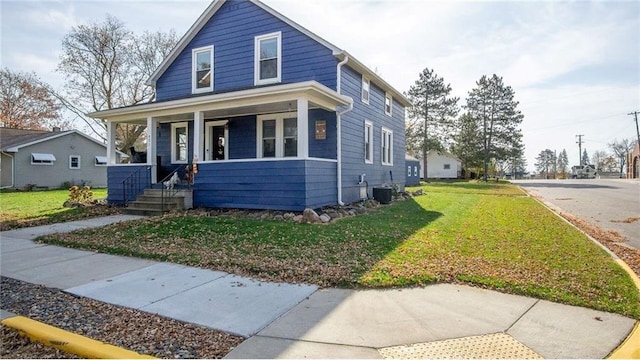 bungalow with central AC unit, covered porch, and a front lawn