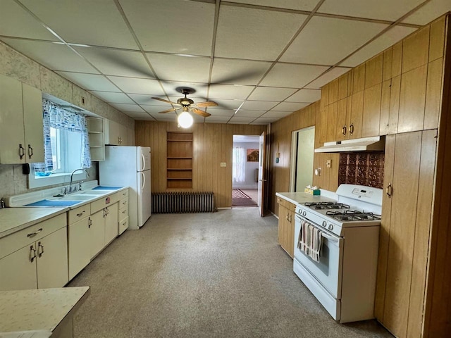 kitchen with radiator heating unit, white appliances, a drop ceiling, and wooden walls