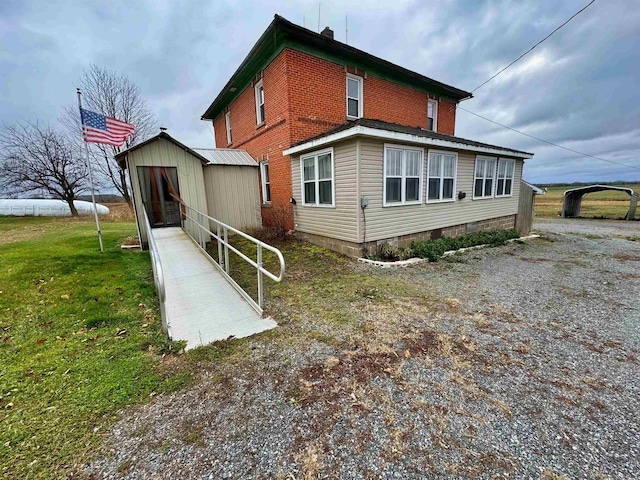 rear view of house featuring a lawn and an outdoor structure