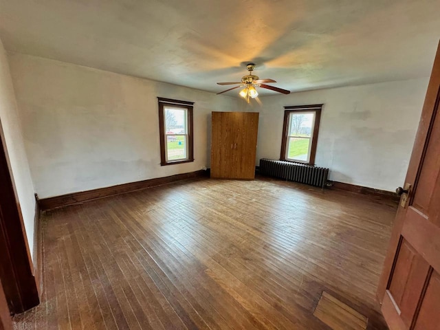 empty room featuring radiator, ceiling fan, and dark wood-type flooring