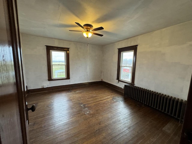 empty room with radiator heating unit, dark hardwood / wood-style flooring, and ceiling fan