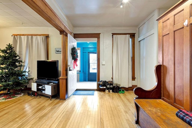 entryway with crown molding and light wood-type flooring