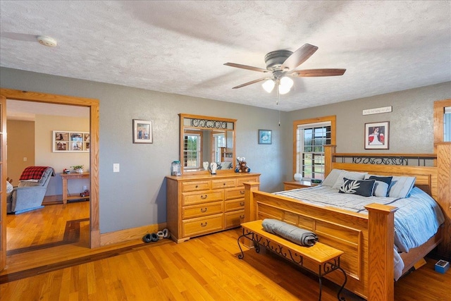 bedroom with ceiling fan, light hardwood / wood-style floors, and a textured ceiling