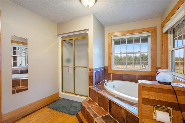 bathroom featuring a healthy amount of sunlight, wood-type flooring, and a textured ceiling