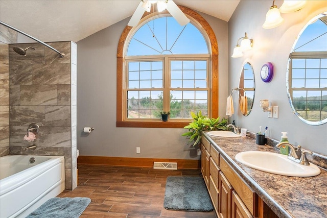 bathroom with plenty of natural light, wood-type flooring, tiled shower / bath, and vaulted ceiling