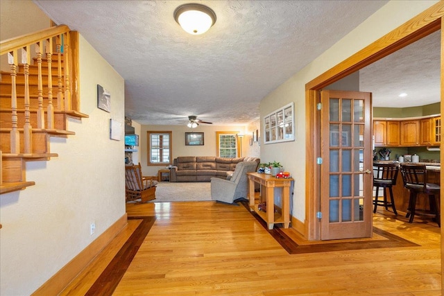 hallway featuring french doors, light hardwood / wood-style flooring, and a textured ceiling