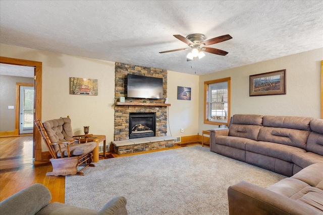 living room with a wealth of natural light, light hardwood / wood-style flooring, ceiling fan, and a textured ceiling