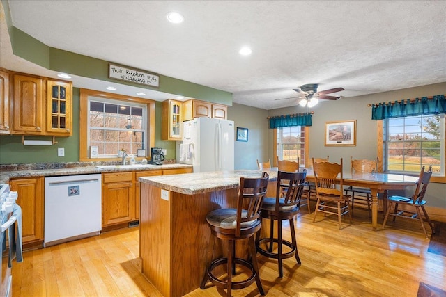 kitchen featuring a kitchen island, white appliances, sink, and a wealth of natural light