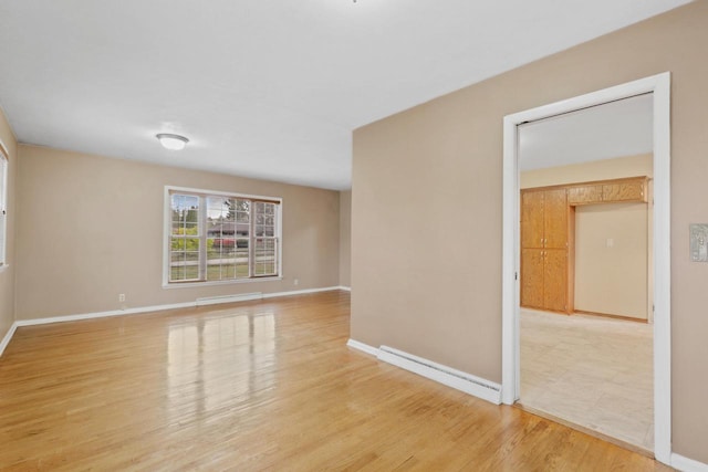 spare room featuring wood-type flooring and a baseboard heating unit