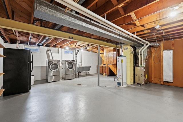 basement with black refrigerator, sink, separate washer and dryer, water heater, and heating unit