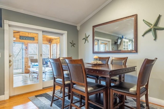 dining room featuring light hardwood / wood-style flooring, lofted ceiling, and ornamental molding