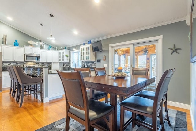 dining space with crown molding, light hardwood / wood-style flooring, and vaulted ceiling