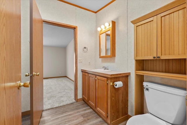 bathroom with toilet, vanity, ornamental molding, and hardwood / wood-style flooring