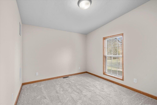 carpeted spare room with a textured ceiling and vaulted ceiling