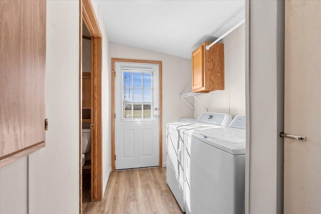 laundry area with washer and dryer, light hardwood / wood-style floors, and cabinets