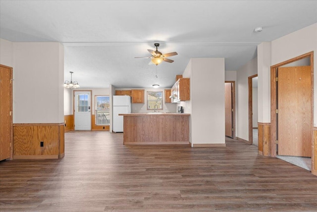 kitchen featuring kitchen peninsula, white refrigerator, dark hardwood / wood-style floors, and wooden walls