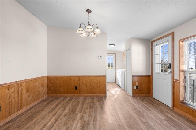 interior space featuring washer and dryer, an inviting chandelier, a healthy amount of sunlight, and hardwood / wood-style flooring