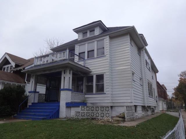 view of front facade featuring a balcony and a front yard