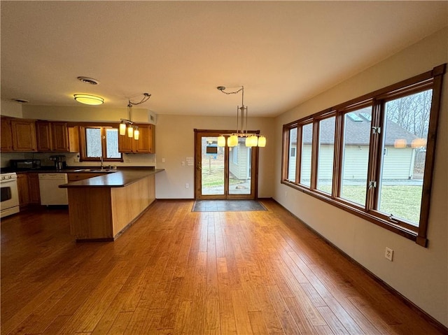 kitchen with pendant lighting, plenty of natural light, white appliances, and kitchen peninsula