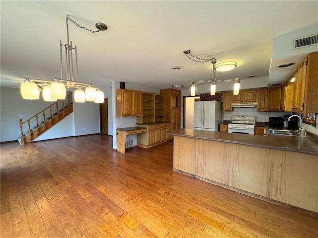 kitchen featuring decorative light fixtures, sink, wood-type flooring, and white appliances