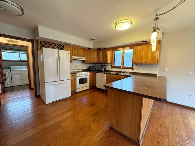 kitchen with kitchen peninsula, plenty of natural light, washer and dryer, and white appliances