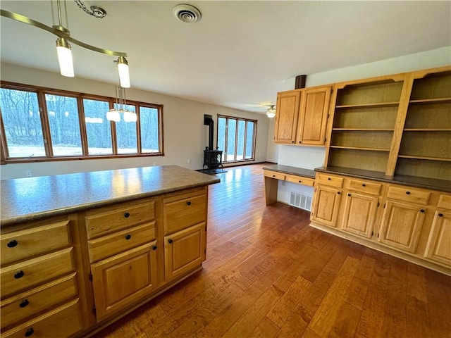 kitchen with dark hardwood / wood-style flooring, decorative light fixtures, a wood stove, and ceiling fan