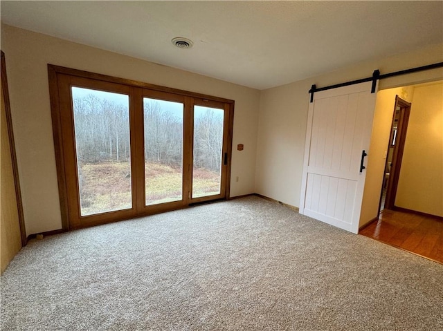 spare room featuring carpet flooring and a barn door