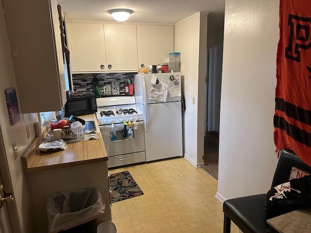 kitchen with backsplash, white fridge, white cabinetry, and stainless steel gas range