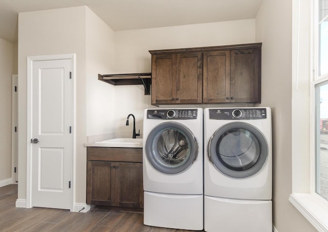 washroom with dark wood-style floors, cabinet space, a sink, washer and dryer, and baseboards