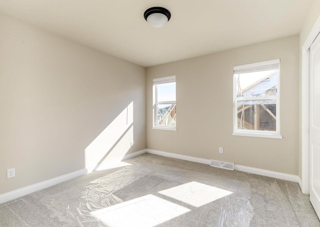 spare room with visible vents, light carpet, and baseboards