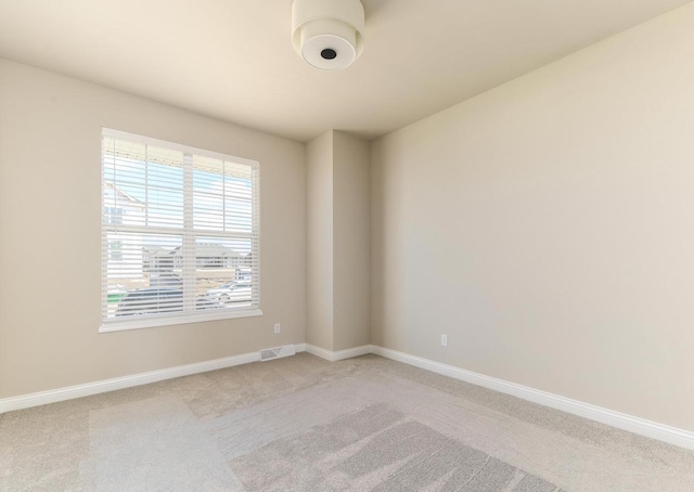 spare room featuring light carpet, visible vents, and baseboards