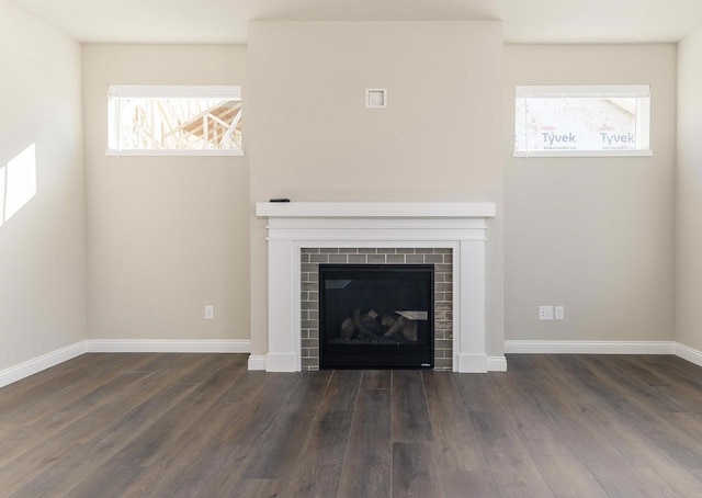 unfurnished living room with dark wood-type flooring, a fireplace, and baseboards