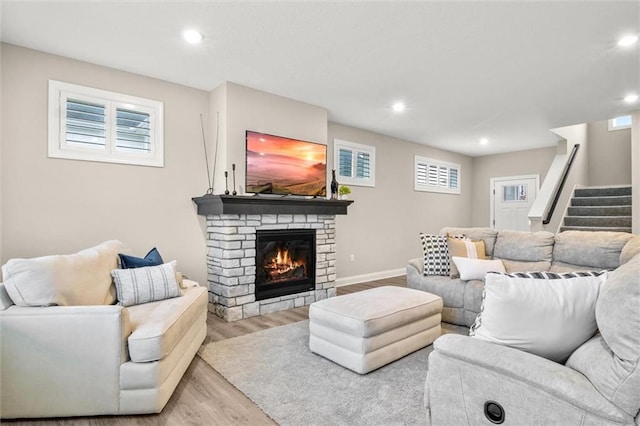 living room with light hardwood / wood-style floors and a stone fireplace